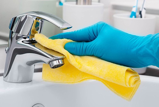 person from housekeeping cleaning water tap with cloth